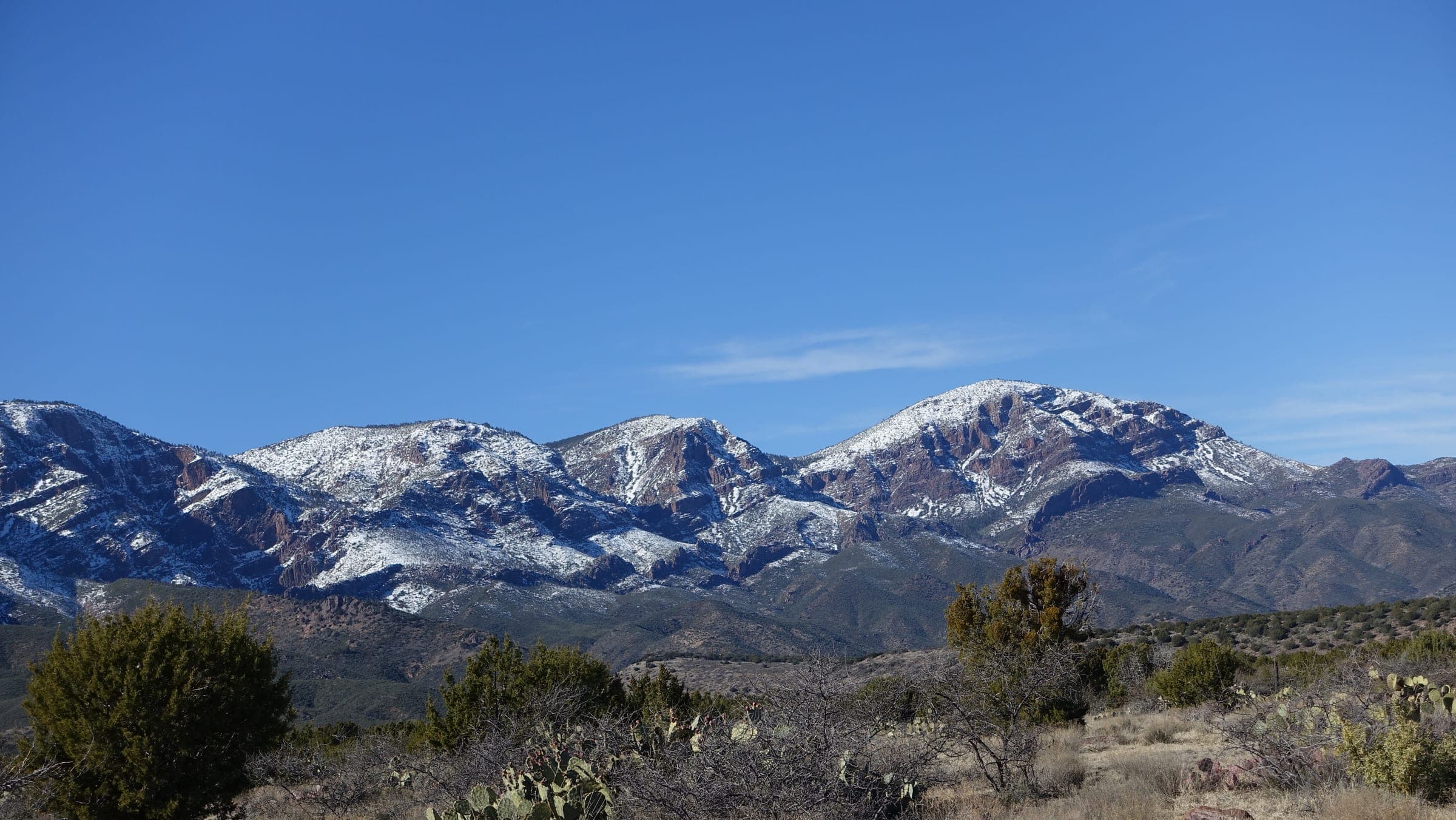 Snow-dusted peaks of the Mazatzal Mountains above juniper and prickly pear near the Barnhardt Trail