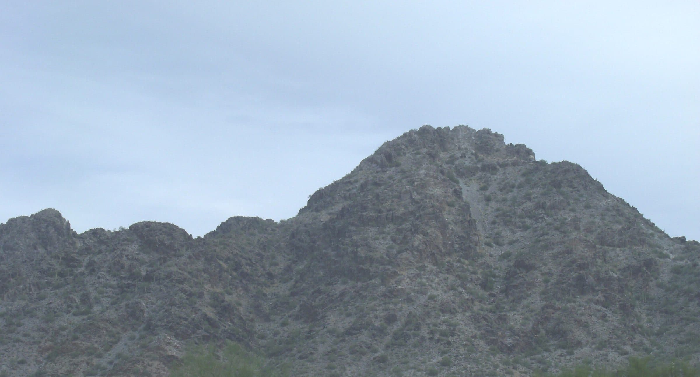 The dark, craggy summit of Piestewa Peak under an overcast sky