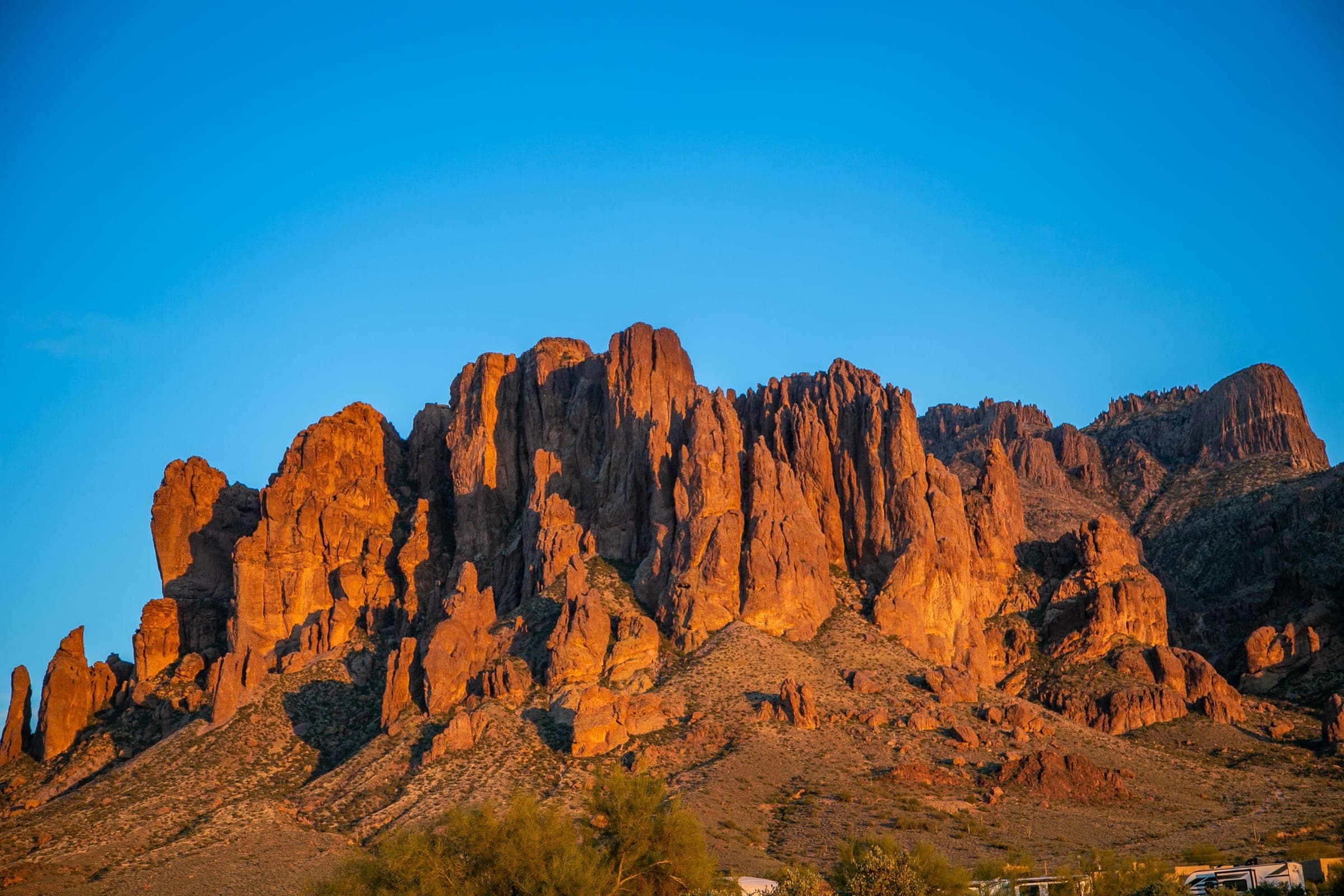 The rock spires of the Superstitions' western face lit orange at sunset above the desert